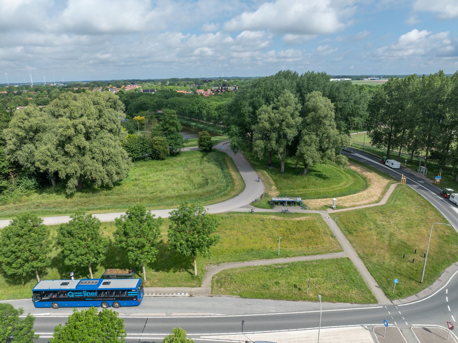 De bushaltes en omgeving bij de rotonde Alkmaarseweg in Middenmeer-Zuid, met een streekbus en fietspad.